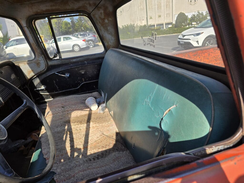 Vintage car interior showing an old bench seat and simple door panel.