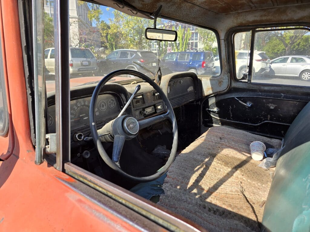 Interior view of a vintage car showing the steering wheel and dashboard.