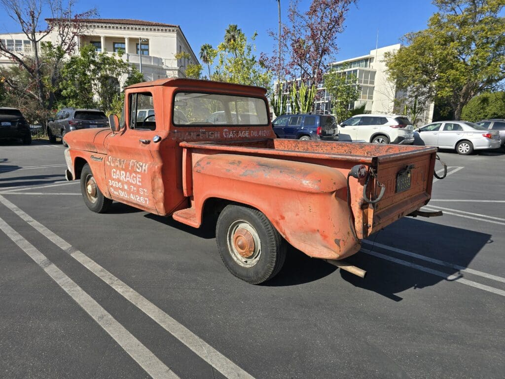 Rusty vintage pickup truck parked outdoors on a sunny day.