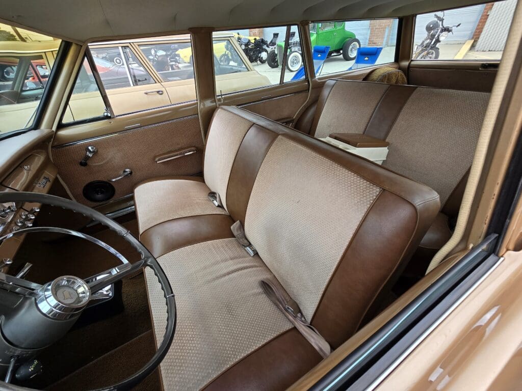 Classic car interior with vintage bench seats in brown and beige upholstery.