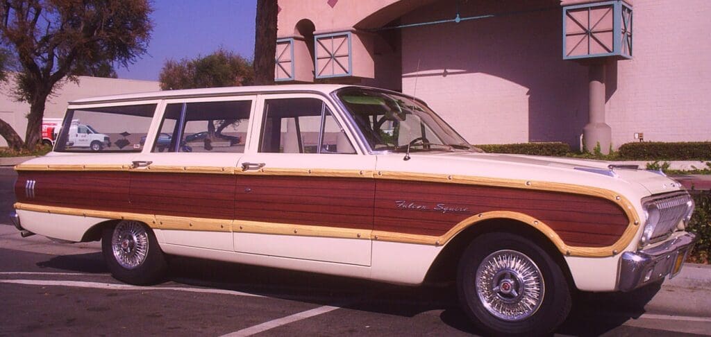 Classic station wagon with wood paneling parked outside a pink building.