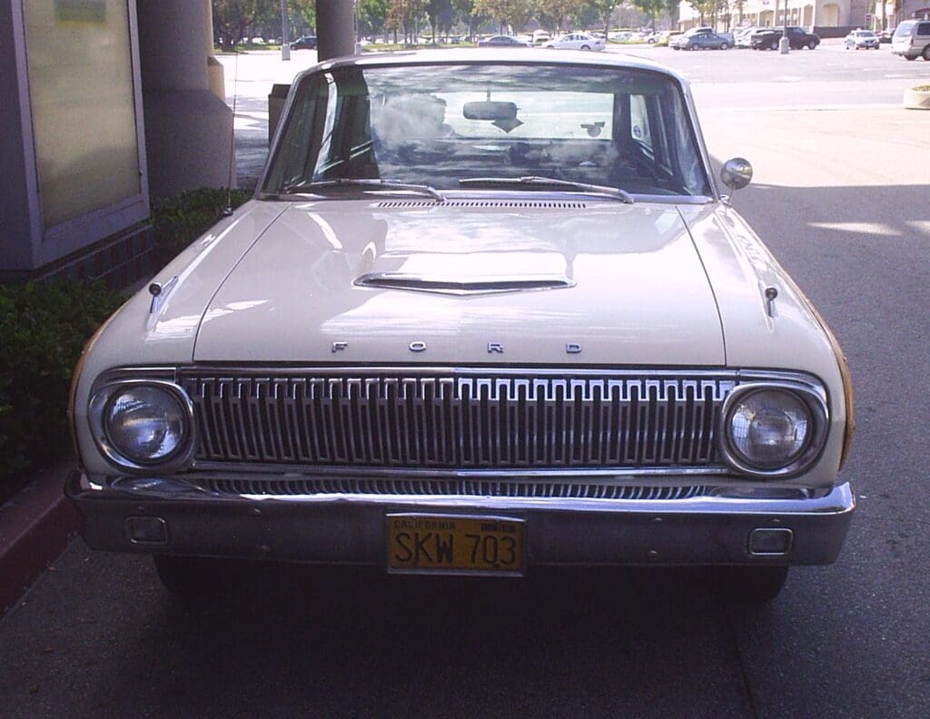 Front view of a vintage white car parked outdoors.