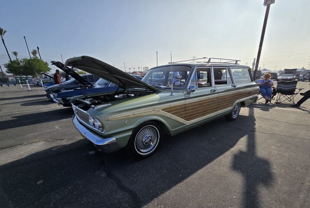 Classic station wagon car with hood open at an outdoor show.