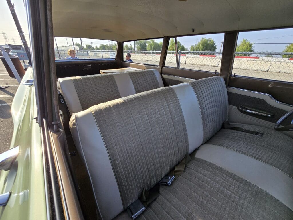 Interior view of a vintage car with gray fabric seats and seat belts.