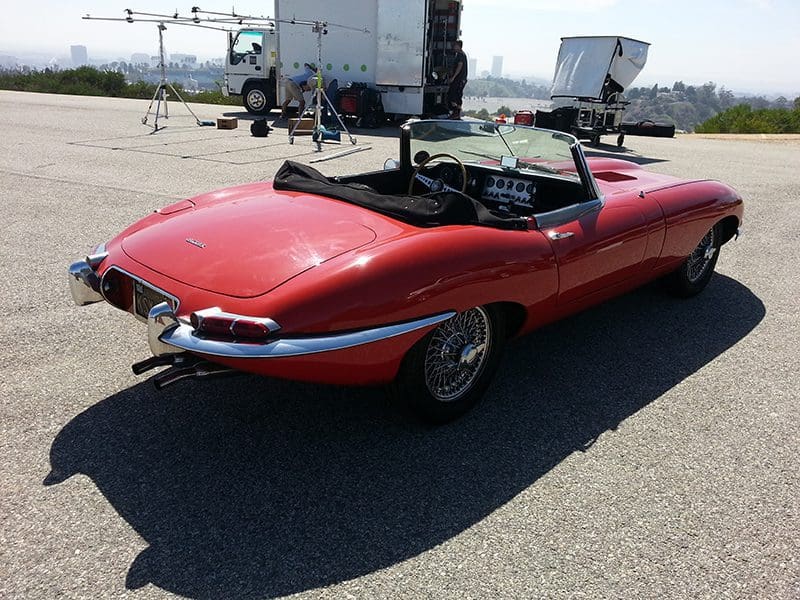 Classic red convertible sports car parked outdoors on a sunny day.