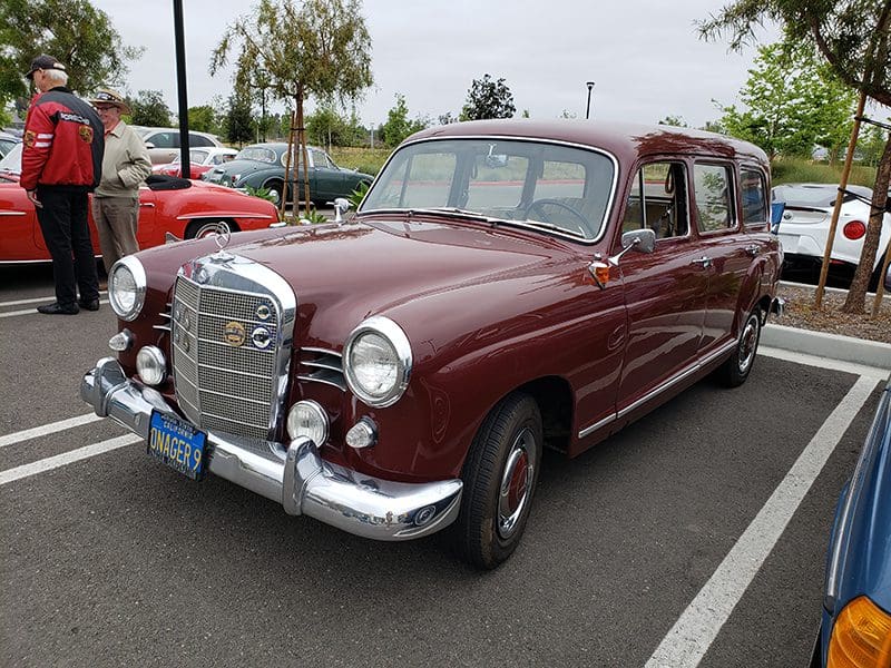 A classic maroon Mercedes-Benz parked outdoors on a cloudy day.