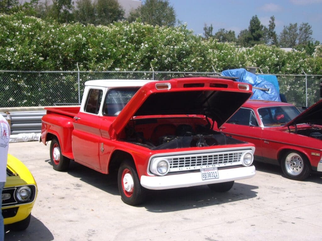 Classic red vintage truck with open hood parked outdoors.