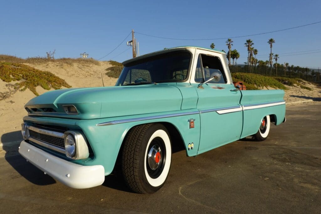 Classic turquoise and white vintage pickup truck parked outdoors on a sunny day.