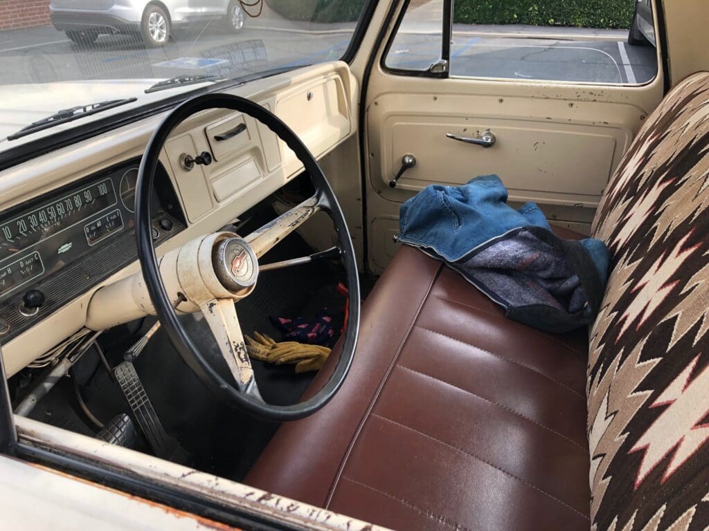 Interior of a vintage car with brown leather seats and a steering wheel.