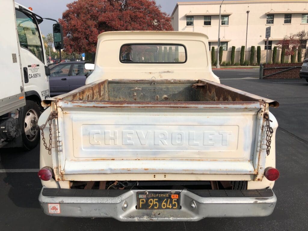 Rear view of a vintage Chevrolet pickup truck with faded paint.