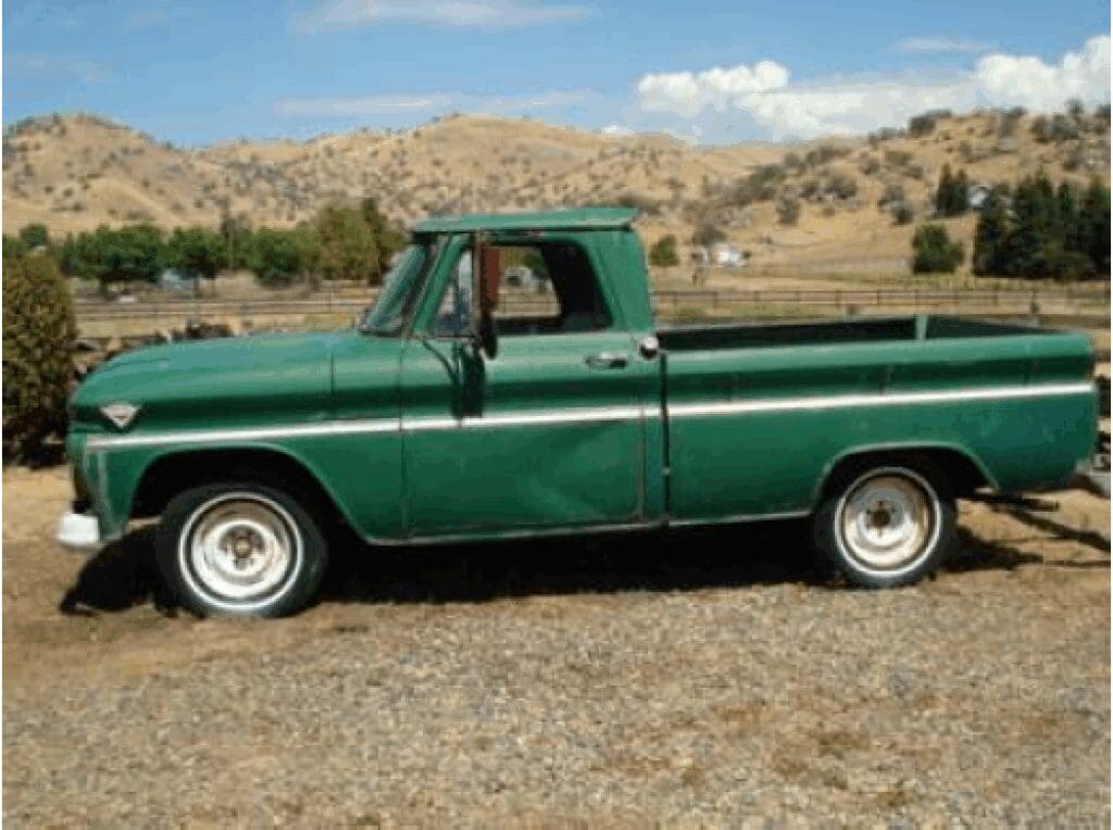 Vintage green pickup truck parked outdoors on a sunny day.