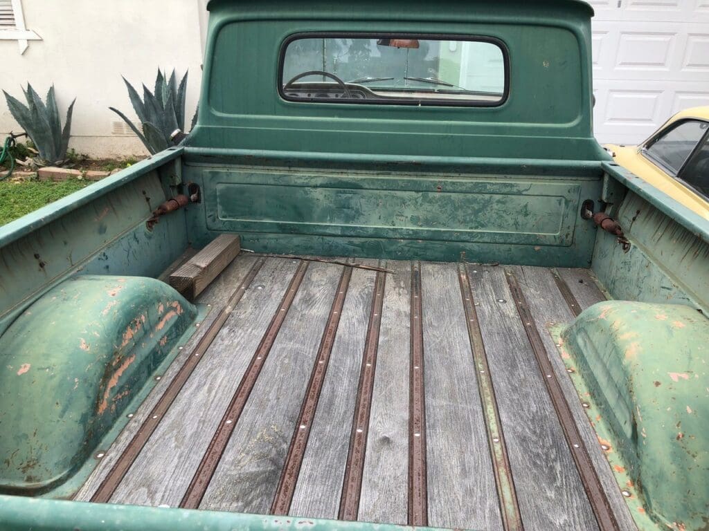 Vintage green pickup truck parked outdoors on a sunny day.