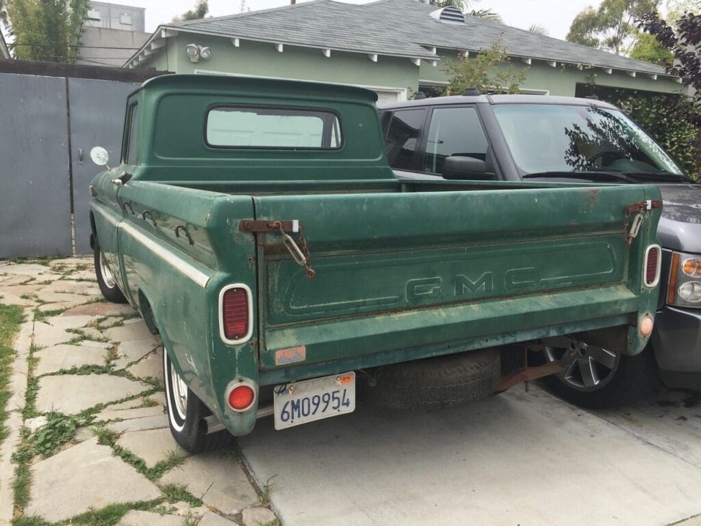 Old green pickup truck parked in a driveway.