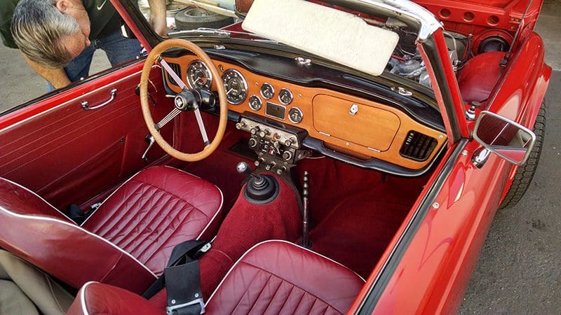 Classic car interior with wooden dashboard and red leather seats.