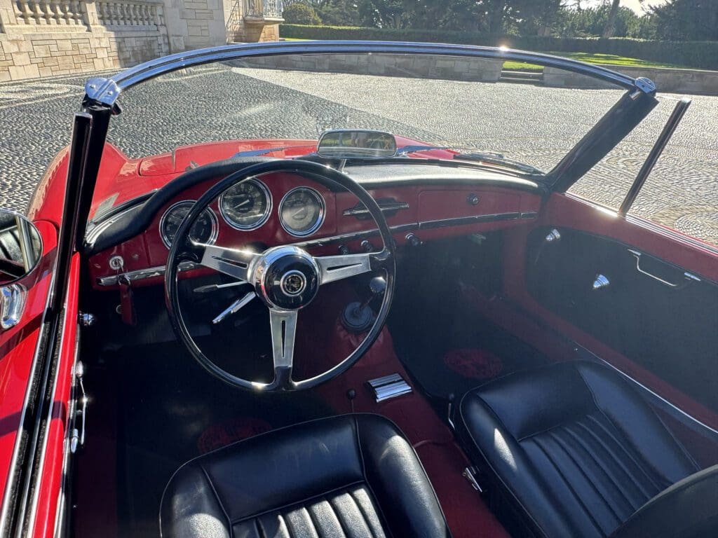 Interior of a vintage red convertible car with black leather seats.