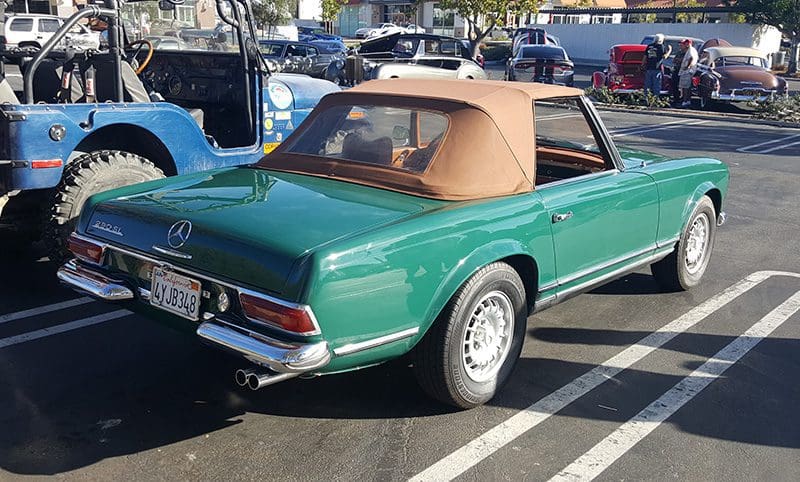 Classic green convertible Mercedes-Benz with a tan soft top parked outdoors.