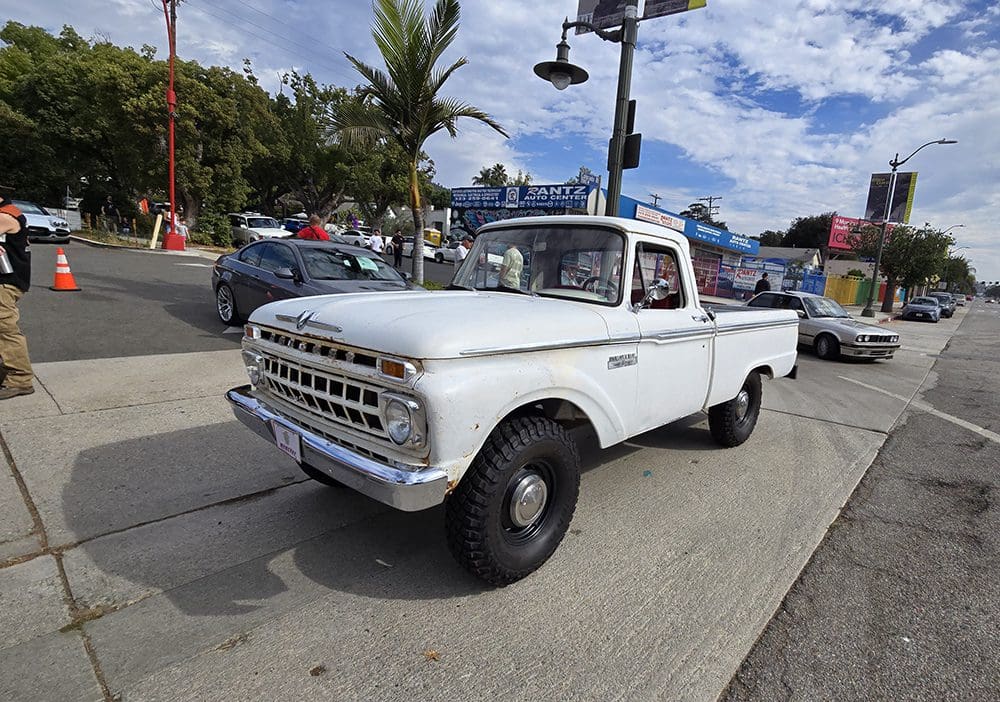 Classic white pickup truck parked outdoors under a partly cloudy sky.