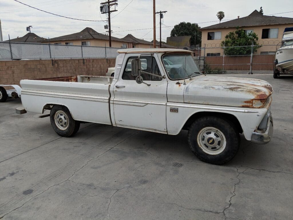 Classic white pickup truck parked on a concrete driveway.