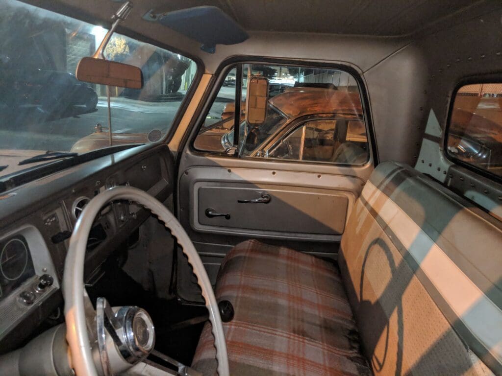 Vintage car interior with plaid seats and a classic steering wheel.