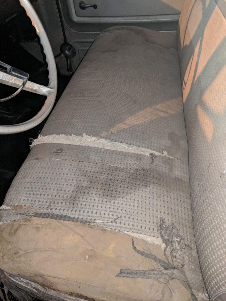 Worn and stained car seat with visible damage and dirt.