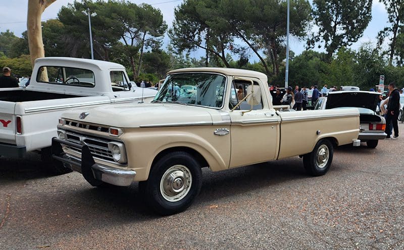 Classic beige vintage pickup truck parked outdoors with trees in background.