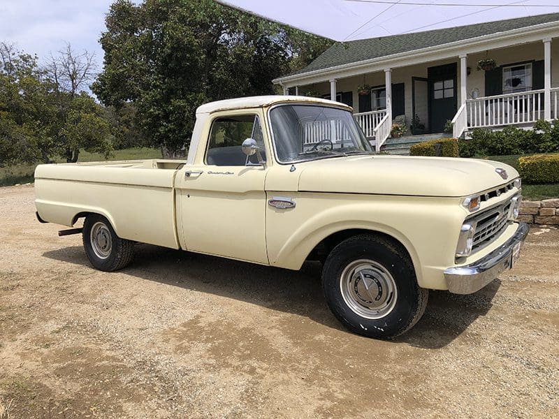 Classic cream-colored vintage pickup truck parked near a house.