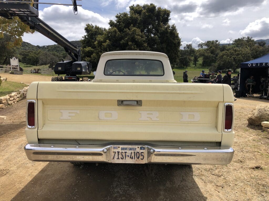 Rear view of a beige vintage pickup truck with a Texas license plate.