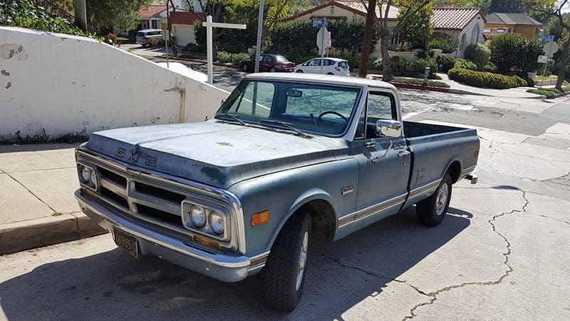 Classic blue vintage pickup truck parked on a sunny residential street.