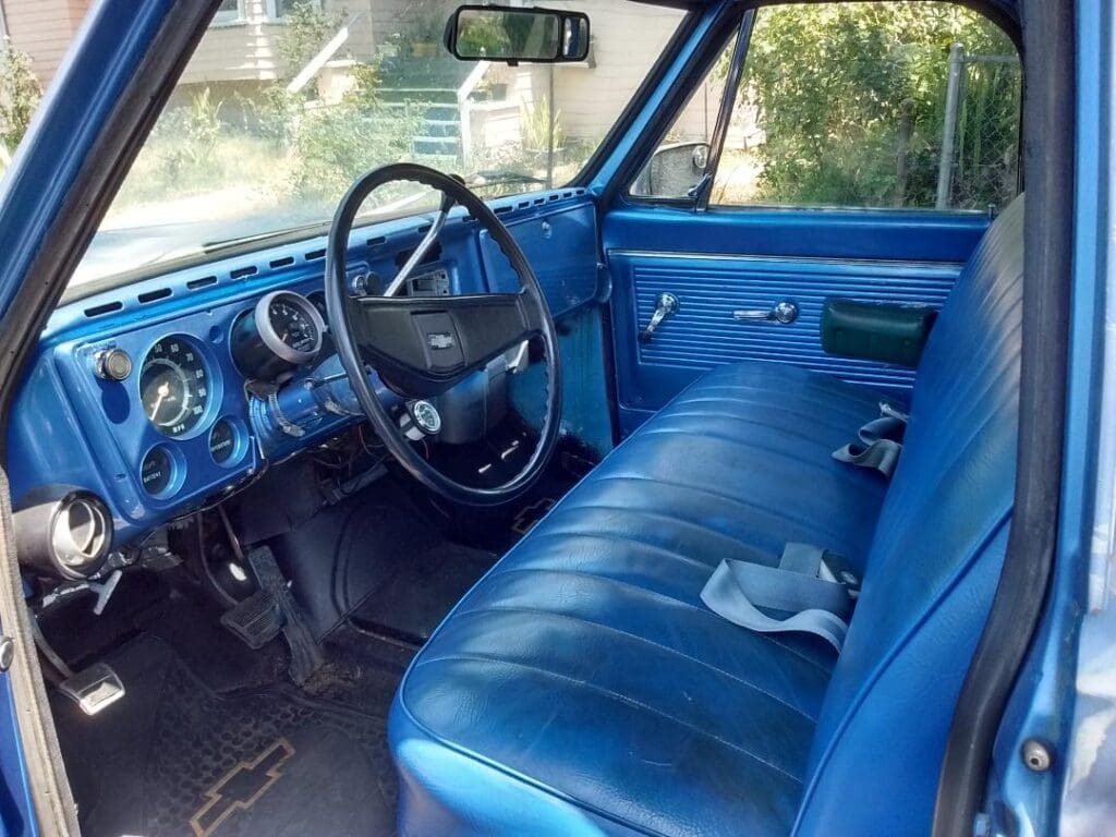 Classic blue vintage car interior with bench seat and simple dashboard.