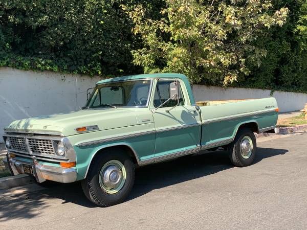 Classic green and white vintage pickup truck parked beside a white wall.