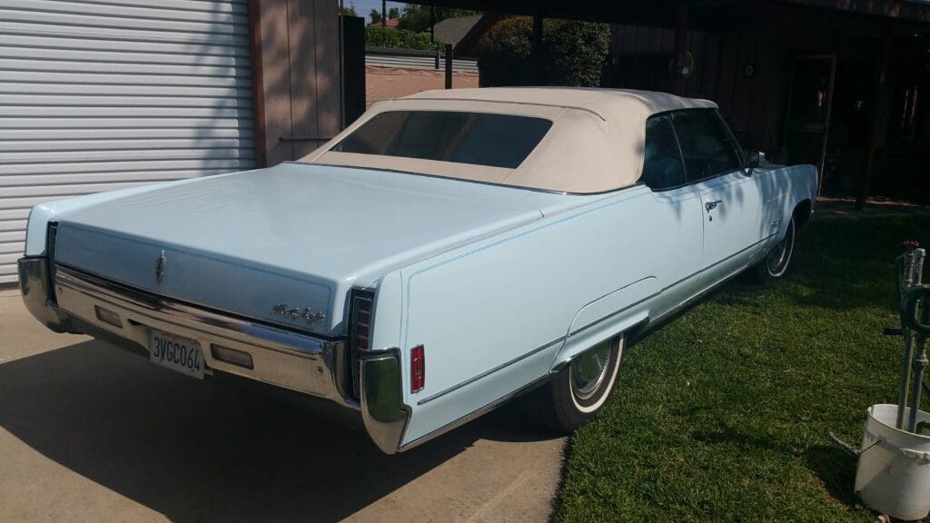 Light blue vintage convertible car parked outside in the sun.