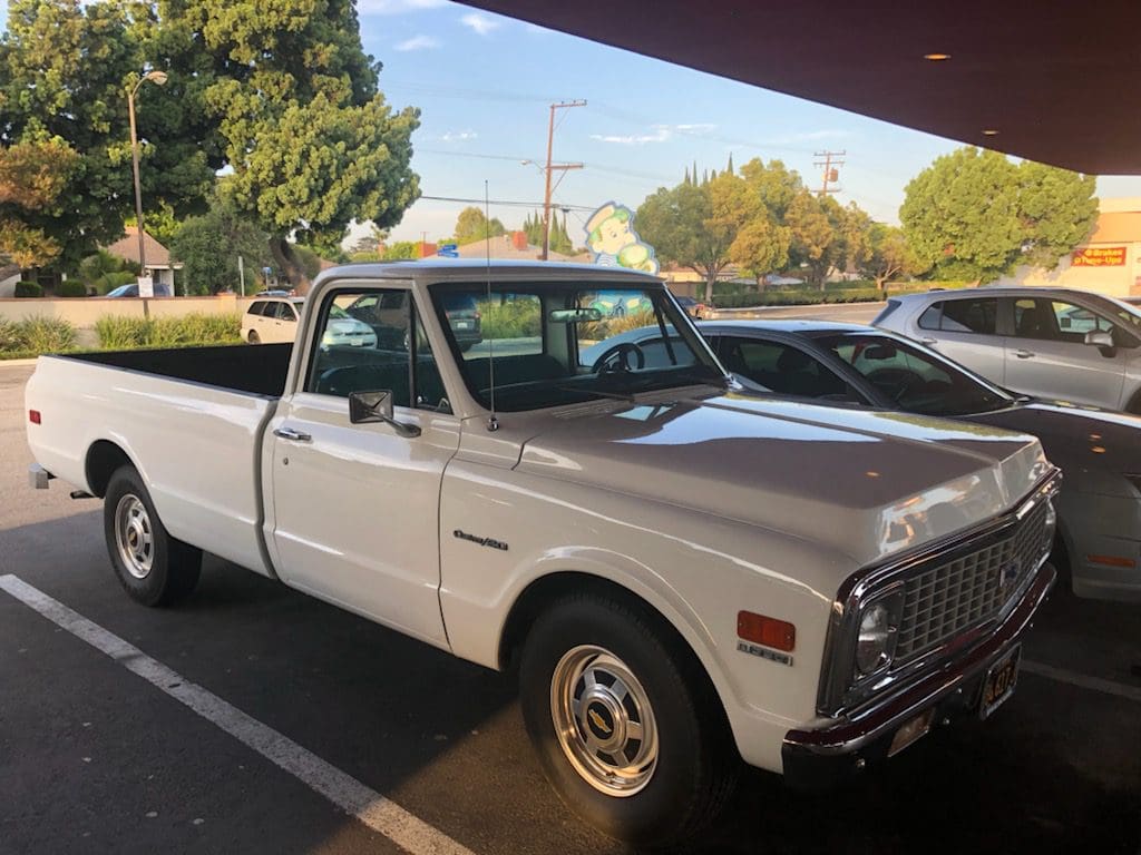 Classic white pickup truck parked under a shade.