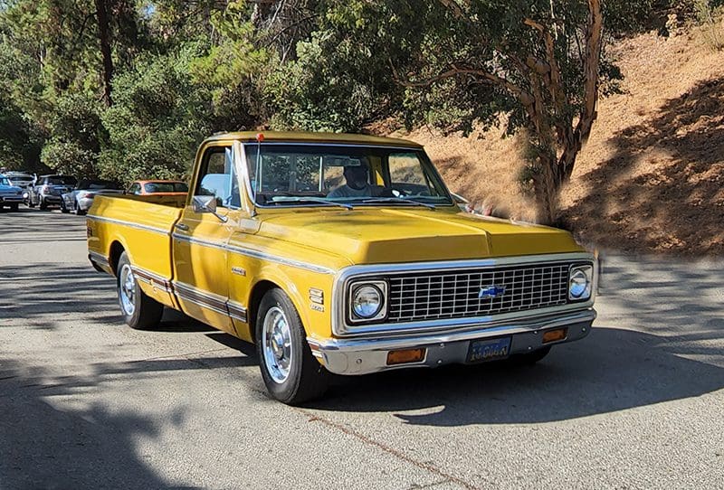 Vintage yellow pickup truck parked on a sunny street.