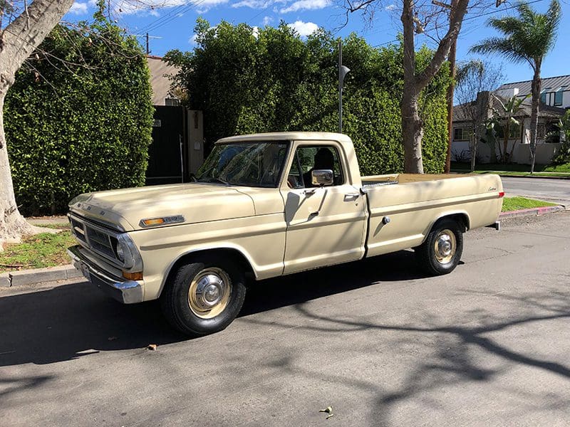 Vintage beige pickup truck parked on a sunny street.