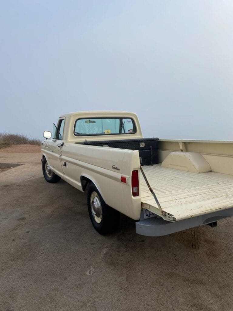 Classic cream-colored vintage pickup truck parked with a clear blue sky.