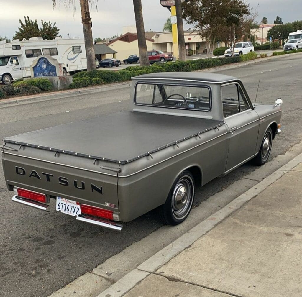 Classic Datsun pickup truck parked on a suburban street.