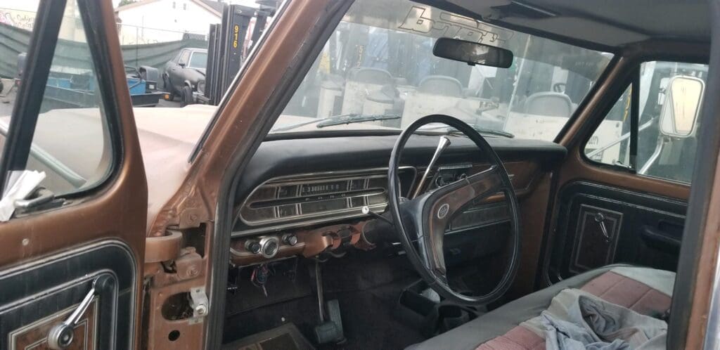 Interior of an old, dusty car with a worn dashboard and steering wheel.