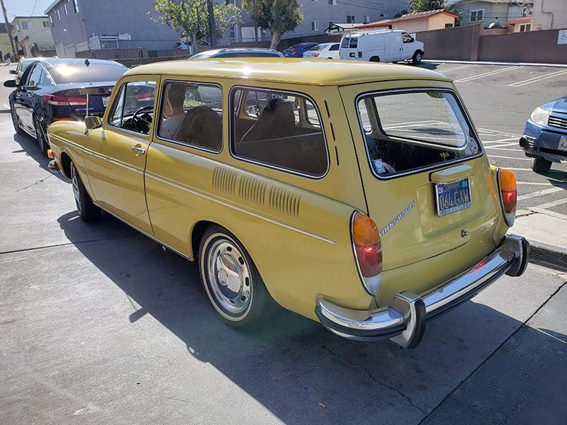 Yellow vintage station wagon parked on a sunny street.