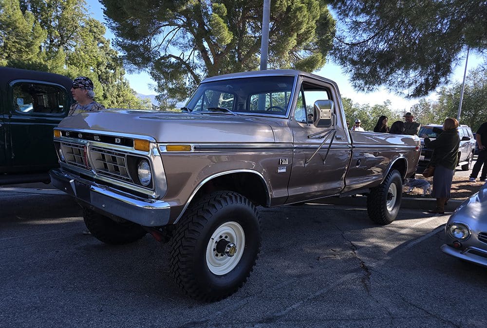Classic brown pickup truck parked under trees on a sunny day.
