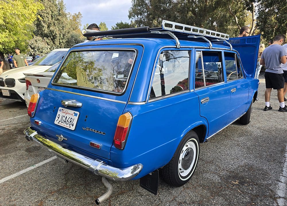Vintage blue station wagon parked outdoors with roof rack.