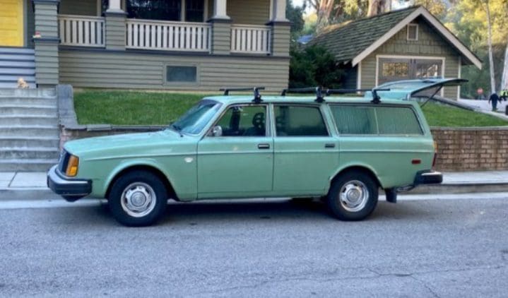 Vintage green station wagon parked on a suburban street.