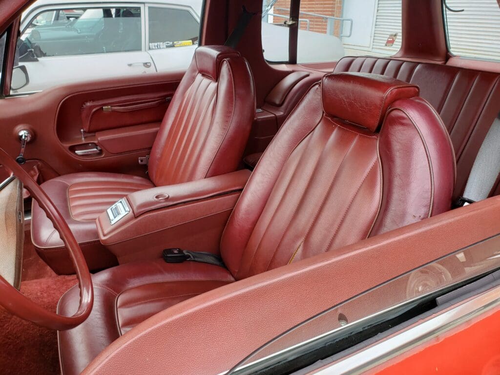 Luxurious vintage car interior with rich red leather seats.