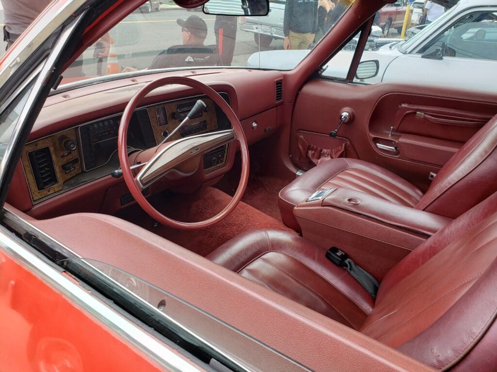 Interior of a vintage red car with leather seats and a classic steering wheel.