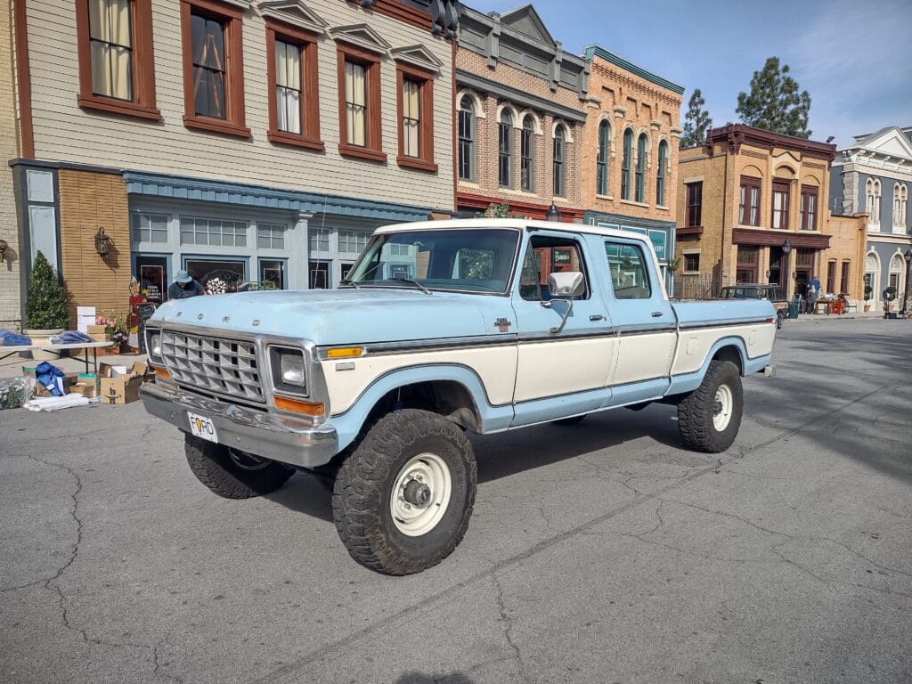 A vintage blue and white pickup truck parked on a city street.