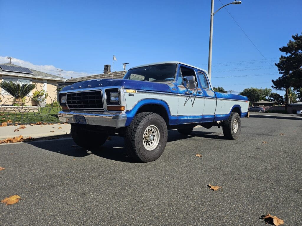 Classic blue and white vintage pickup truck parked on a sunny street.