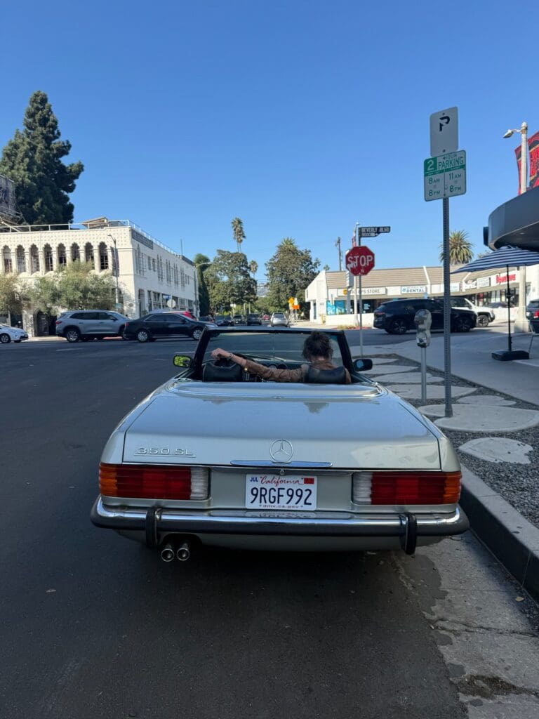 Classic white convertible car parked on a sunny city street.