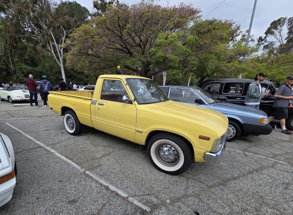 Yellow vintage pickup truck parked outdoors among other vehicles.
