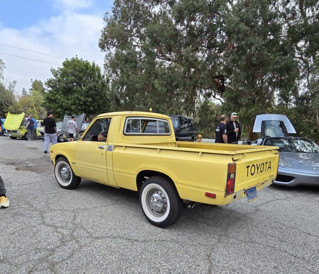 Yellow vintage pickup truck parked outdoors among other vehicles.