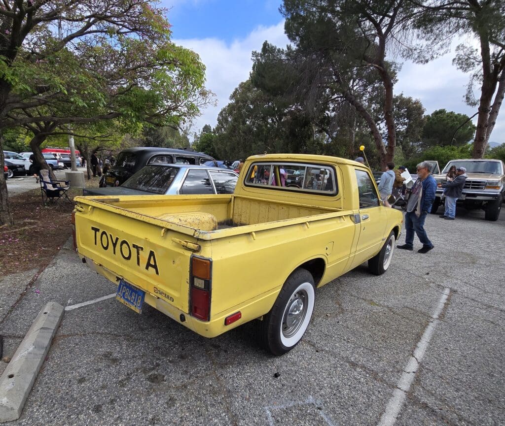 Yellow vintage pickup truck parked outdoors among other vehicles.