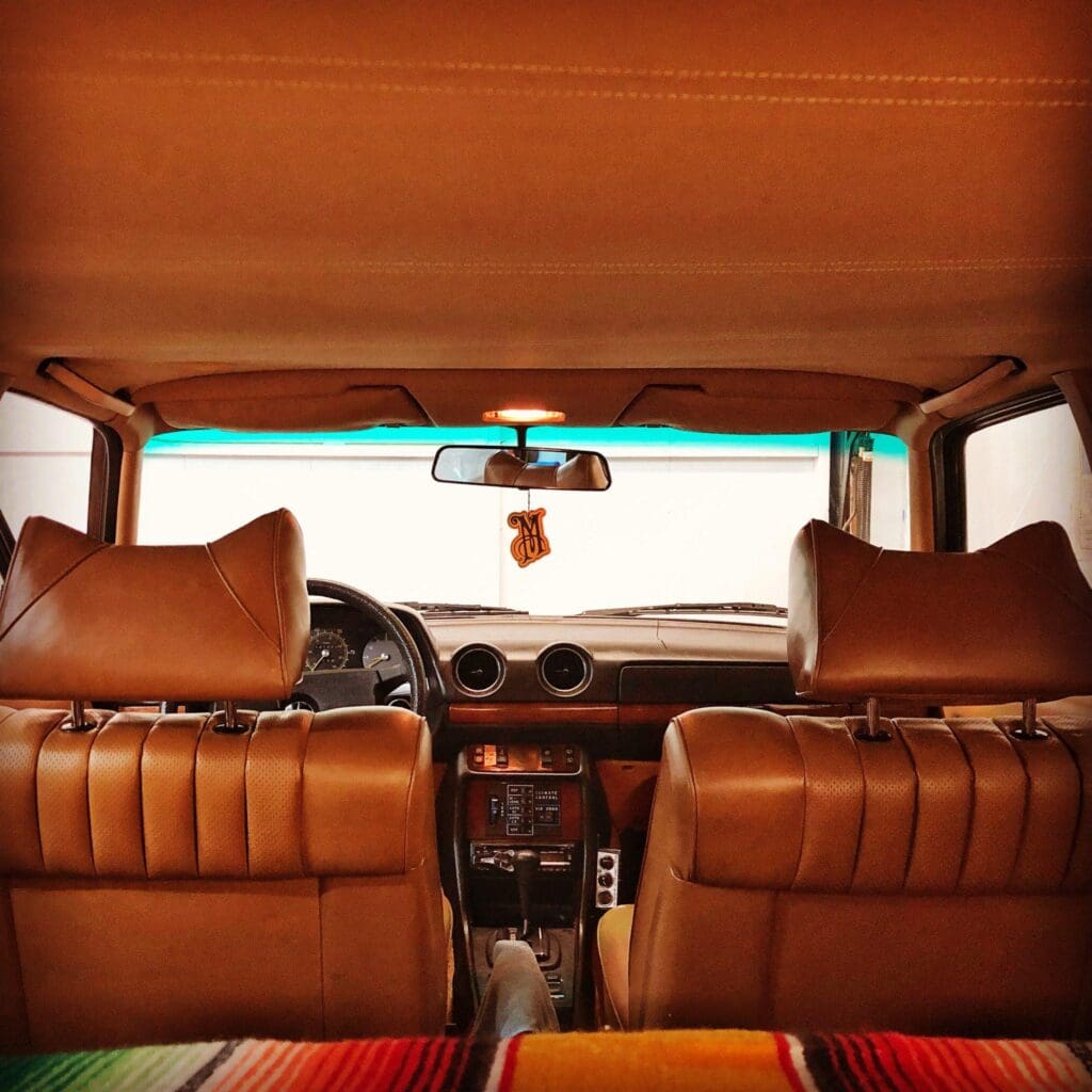 Interior of a vintage car with brown leather seats and wooden dashboard.